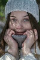 Crop shot of teenager girl smiling, holding collar of sweater with his hands in cold winter weather photo