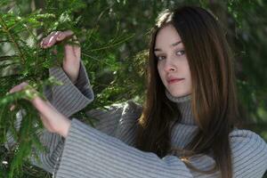 Portrait of teenager with long hair, without make-up looking at camera on background pine woodland photo