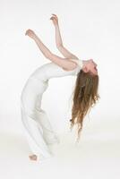 Full length barefoot young woman with eyes closed having fun while bending over backwards on white photo