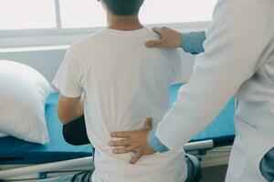 Doctor or physical therapist examines back pain and spinal area to give advice within the rehabilitation center. photo