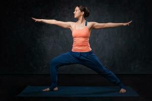 Woman practices yoga asana utthita Virabhadrasana photo
