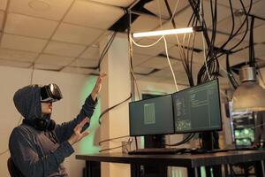 Hacker coding spyware in vr, cracking password in metaverse, hacking server, stealing electronic information. Cyberattack, internet criminal developing malware in virtual reality headset photo