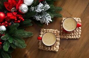 Top view of two red mugs with coffee in on wooden table with Christmas decorations photo