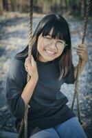 face of asian teenager relaxing on rope swing photo