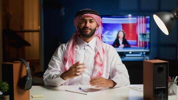 Portrait of smiling arab man engaged in elearning webinar video conference with teacher. Middle Eastern student in online videocall greeting tutor, paying attention to his words and taking notes