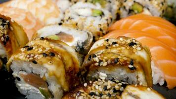 Sushi rolls in variety mix on black stone plate. Dolly slide parallax type footage video