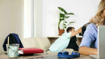 uomo fa un' lotto di rumore Guardando un' sport gioco su il tv mentre sua fidanzata cerca per opera su il computer nel il stesso camera. cremagliera messa a fuoco dolly cursore 4k metraggio video