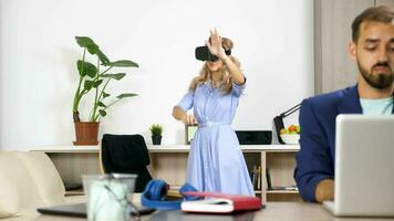 Beautiful woman exploring virtual reality while her boyfriend works on the computer in the same room. Dolly slider rack focus 4K footage video