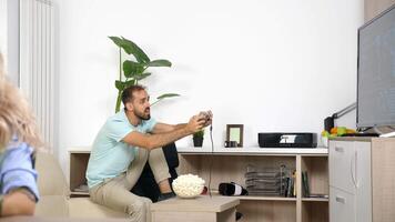 Noisy boyfriend plays video game while freelancer girlfriend is working at home. Rack focus from men to woman. Conceptual dolly slide 4K footage of freelancing struggle.