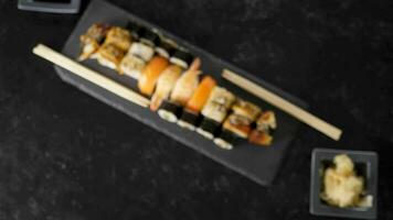 Top view zoom in on delicious traditional japanese sushi rolls on black stone plate video