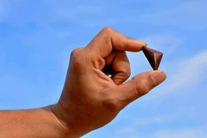 a person holding a gemstone against a blue sky photo