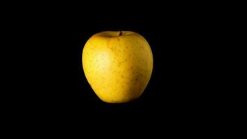 Yellow apple rotates isolated on black background slow motion video 360