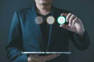 a businessman choose the virtual screen on the happy smile face icon to give satisfaction in service.rating very impressed.customer review service and Satisfaction concept photo