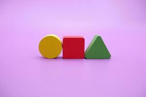 Set of colorful wooden shape toy. Square, triangle and round on Purple background photo