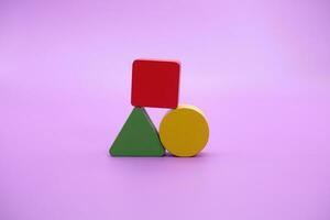 conjunto de vistoso de madera forma juguete. cuadrado, triángulo y redondo en púrpura antecedentes foto