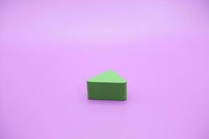 verde de madera forma juguete. triángulo en púrpura antecedentes foto