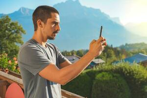 Young man taking a picture of a beautiful scenic mountain background. Attractive Traveler. photo