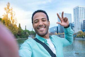 Young African American man taking a selfie looking at camera smiling Tourist student photo