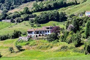 a house on a hillside with green grass and trees photo