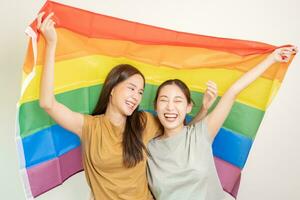 LGBT group. Good looking lesbian couples smile brightly cover rainbow flags. Asian young couple hugging each other happily, lover in love, bisexualities, homosexuality, liberty, expression, happy life photo