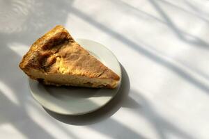 Slice of cheese pie on white plate and white background photo