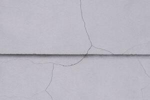 Crack line texture on surface of concrete fence wall background outside of building, close up shot with copy space photo