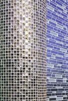Geometric pattern of modern beige mosaic pillar and blue ceramic tile wall decoration background in vertical frame with light reflection on surface, perspective side view photo