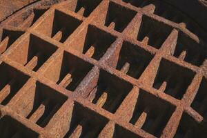 Light and shadow on backside surface of the old rusty manhole cover photo