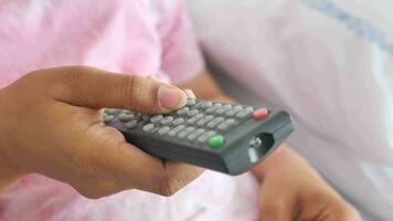 close-up da mão de mulheres segurando o controle remoto da tv. video