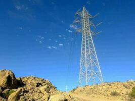 a large electricity tower stands in the middle of a rocky hill photo