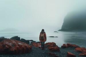 ai generado un joven mujer en pie en un pedregoso playa en el niebla, un mujer solo mirando a un brumoso mar, experimentando aventuras estilo de vida al aire libre, expresando soledad, triste emociones, ai generado foto