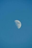 the moon is seen in a blue sky photo