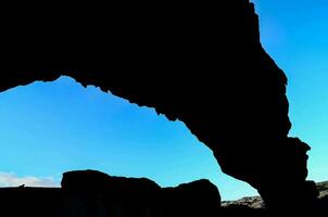 a silhouette of an arched rock formation photo