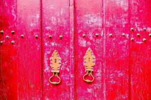 a red wooden door with two brass handles photo