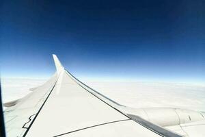 an airplane wing with a blue sky and clouds in the background photo