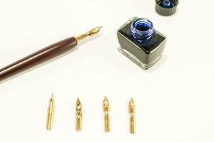 a fountain pen, nibs, and a bottle of ink photo