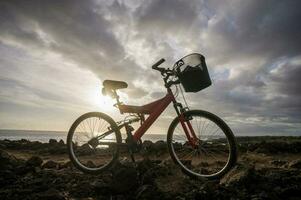 a red bike with a basket on it is sitting on a rocky hill photo