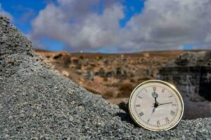 a clock sitting on top of rocks in front of a desert photo