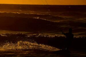 a man kite boarding in the ocean at sunset photo