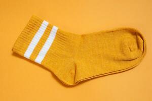 Orange sock isolated on orange background. Top view. photo