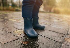 Close-up of a child in rubber boots on wet pavement after rain photo