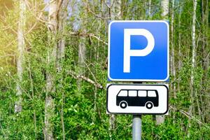 Close-up of a road sign for bus parking against a forest backdrop photo