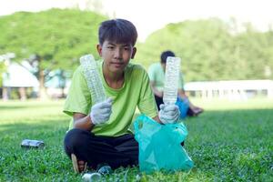 un asiático chico es un estudiante en el ambiental club y su amigos ayuda recoger y ordenar residuos el plastico agua botellas y vaso botellas para reciclaje o reutilizar. en el concepto de ahorro el mundo. foto