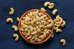 Roasted cashew nuts in a bowl on a blue background, top view photo