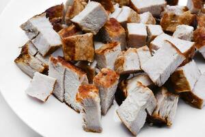 Pieces of fried pork meat on a white plate. Juicy and delicious pieces of barbecue meat. photo