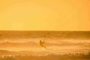 a man kite boarding in the ocean at sunset photo