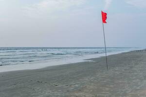 red flag on beach on sea or ocean at sunset as symbol of danger. The sea state is considered dangerous and swimming is prohibited. photo