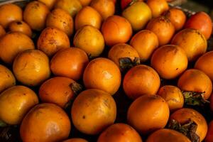 Ripe orange persimmons. on the table in the market. A bunch of organic persimmon fruits at a local farmers market in Dalat city, Vietnam. Persimmon background. Flat lay. photo