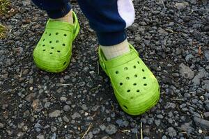 Photo children feet in garden green crocs against