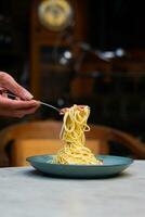 the hand that is lifting the spaghetti on the plate photo